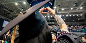 Graduate making heart with fingers